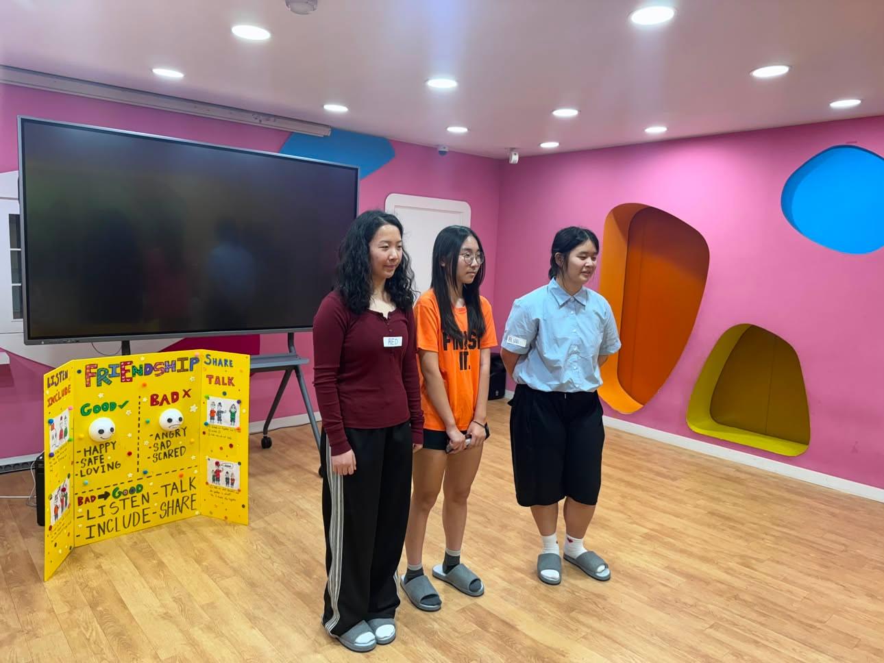 Three Tiny Thoughts presenters beside a Friendship poster contrasting good feelings (happy, safe, loving) with bad feelings (angry, sad, scared), listing Listen, Talk, Include, Share as ways to repair a relationship.